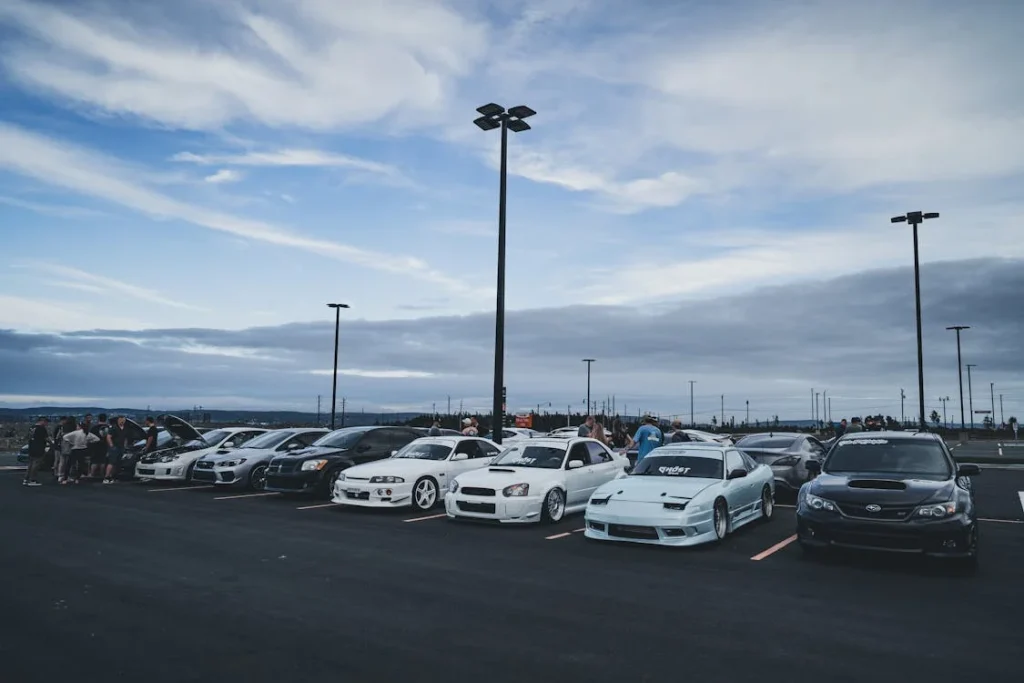 Fotografía de un animado encuentro automovilístico al aire libre, mostrando entusiastas reunidos alrededor de autos clásicos y modernos, destacando la pasión compartida y la comunidad unida por el amor a los vehículos.